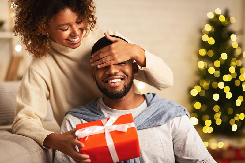 A woman surprises a man, reflecting ideas on what to get a man for Christmas.