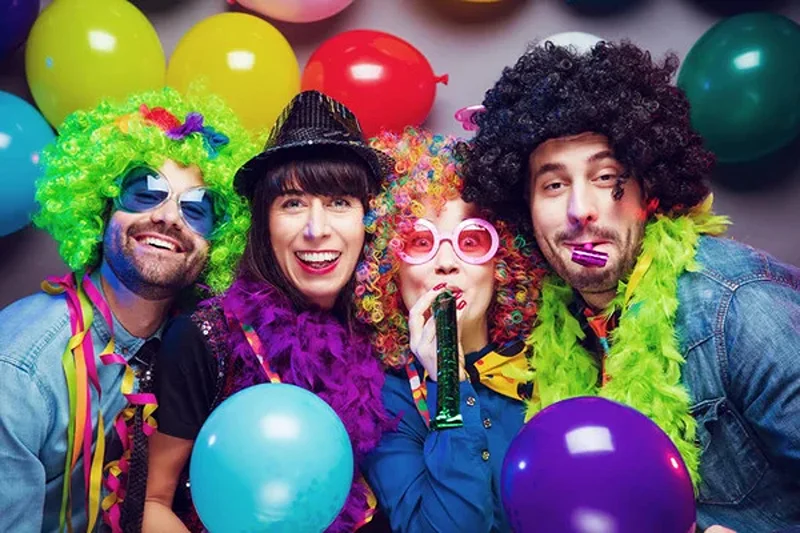 Friends in costume blowing balloons, showcasing 21st birthday ideas girl will love.