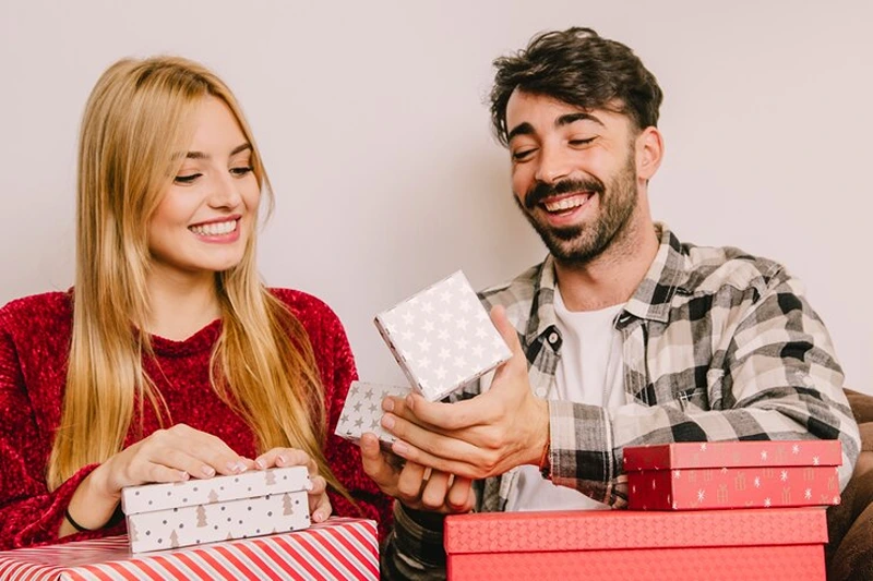 A man excitedly unwraps his present, highlighting perfect gifts for men for Christmas.