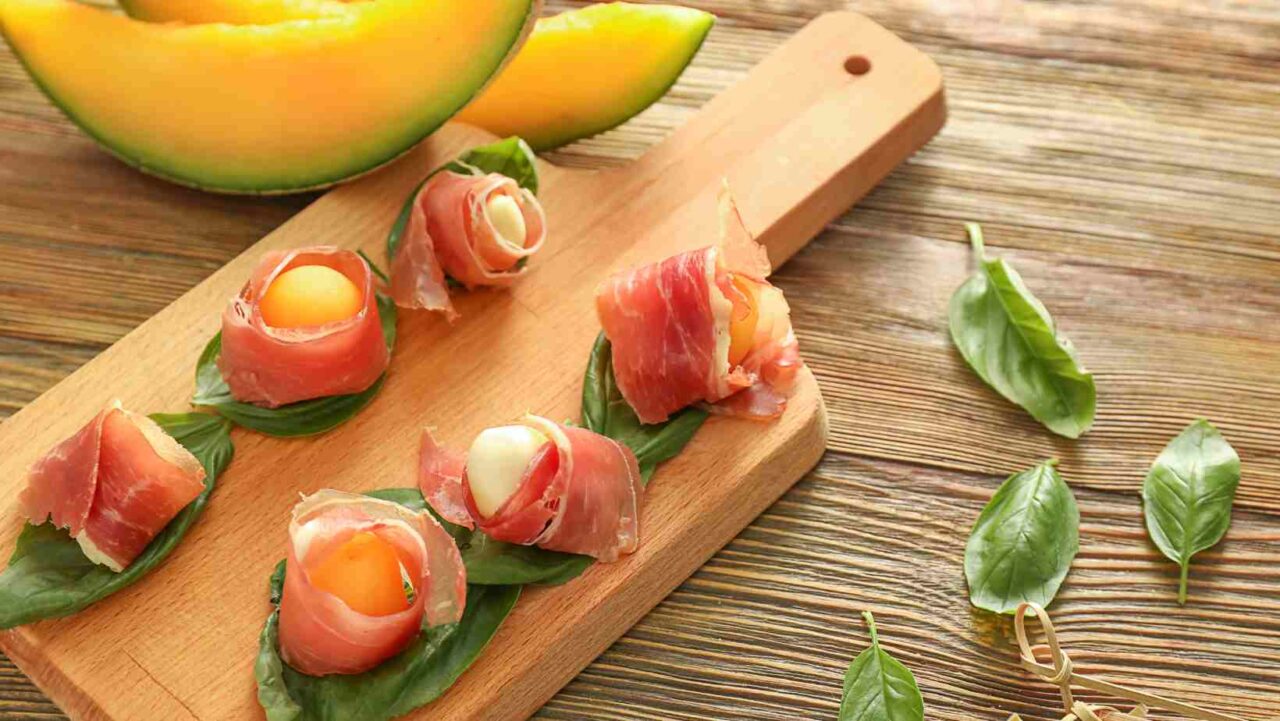 Prosciutto-wrapped melon on wooden canape presentation platter